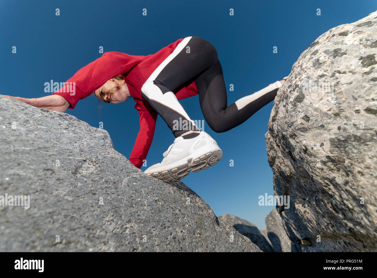woman clambering across rocks, bouldering. Stock Photo