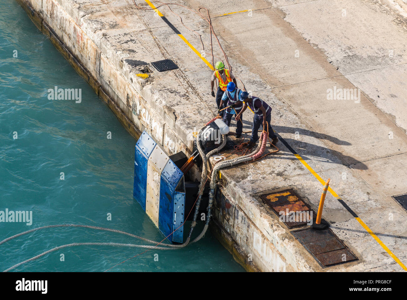 Bridgetown, Barbados - December 18, 2016: Port workers on mooring rope of a ship in harbor of Bridgetown port, Barbados island, Caribbean. Stock Photo