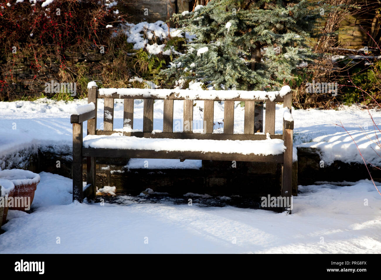 Wooden Garden Bench Covered In Snow On A Garden Patio In England