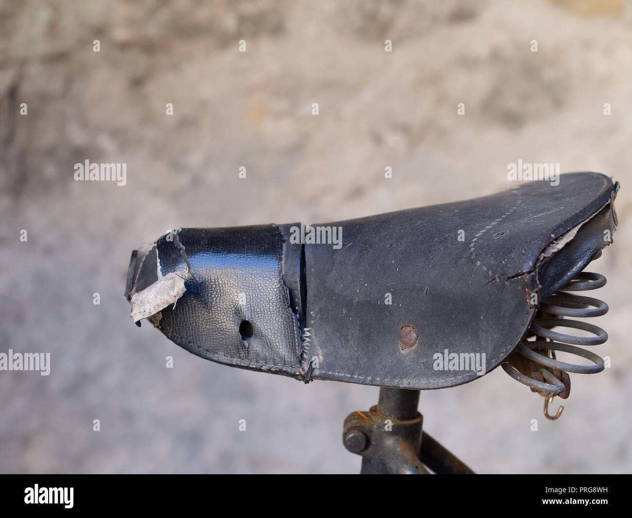 Old leather bicycle saddle, seat, torn with visible springs. Vintage  Stock Photo