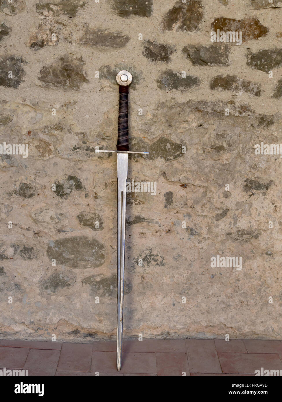 Medieval sword leaning on stone wall. Stock Photo