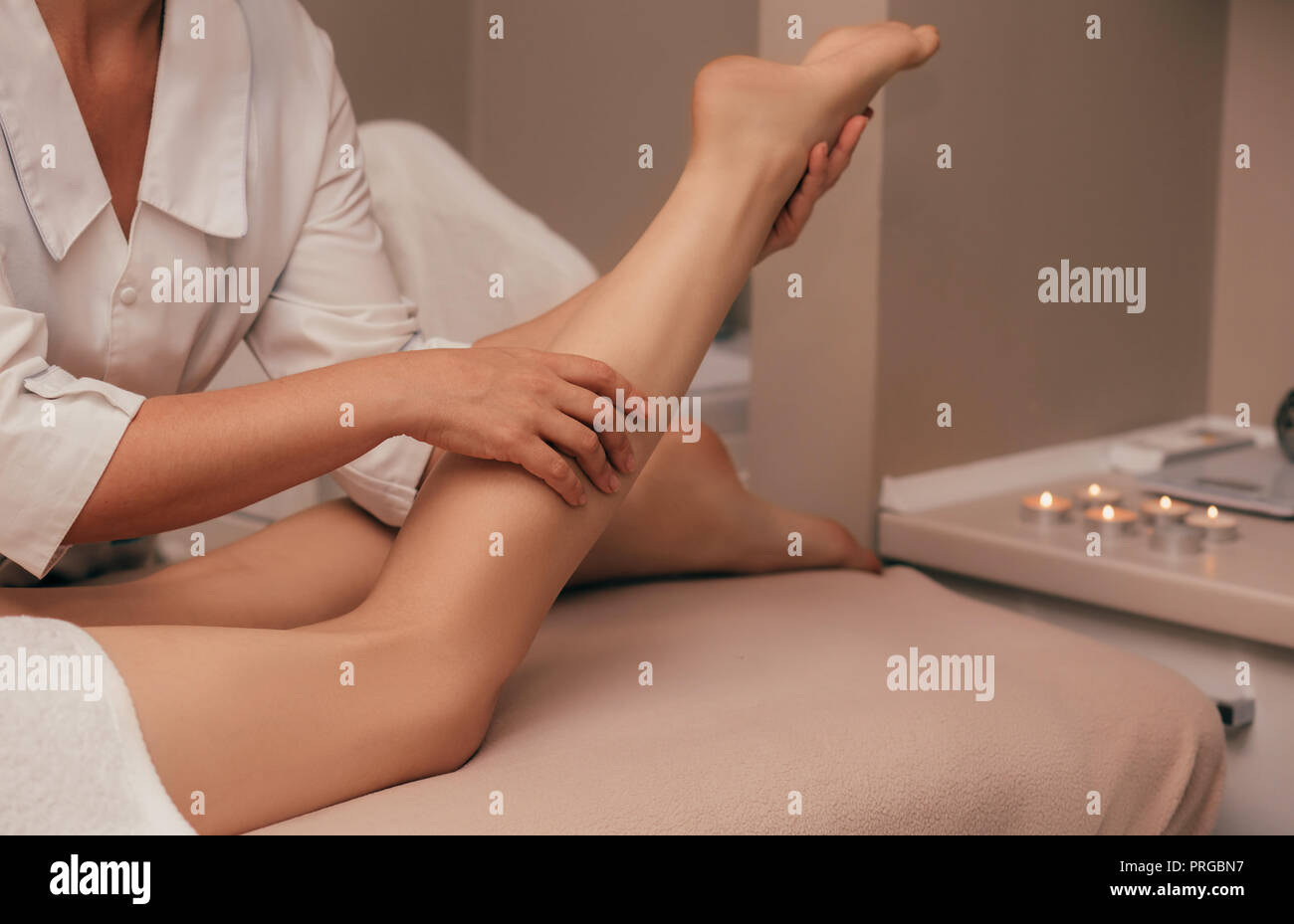 Closeup masseuse giving woman a leg massage Stock Photo