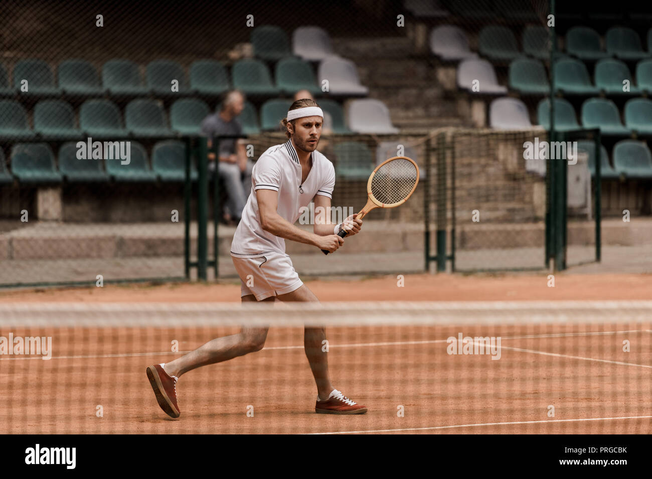 concentrated retro styled man playing tennis at court Stock Photo