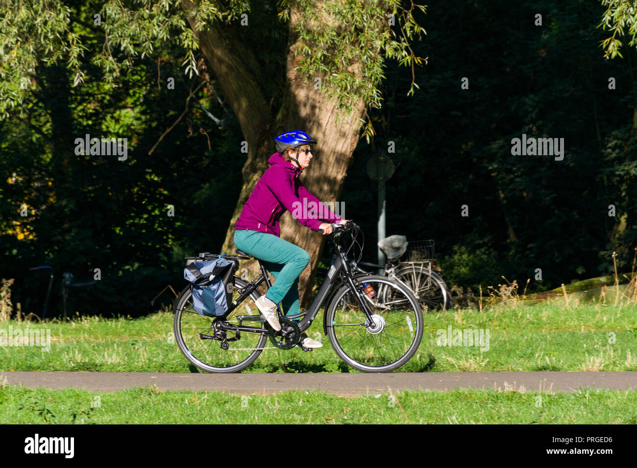 A woman cyclist cycling on a path on a sunny Summer day, Cambridge, UK Stock Photo