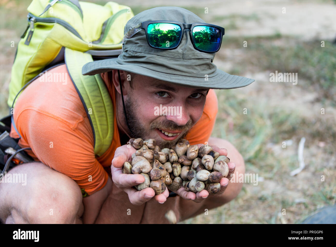 man eats nuts isolated on a light background. Man shows a set of nuts. Stock Photo
