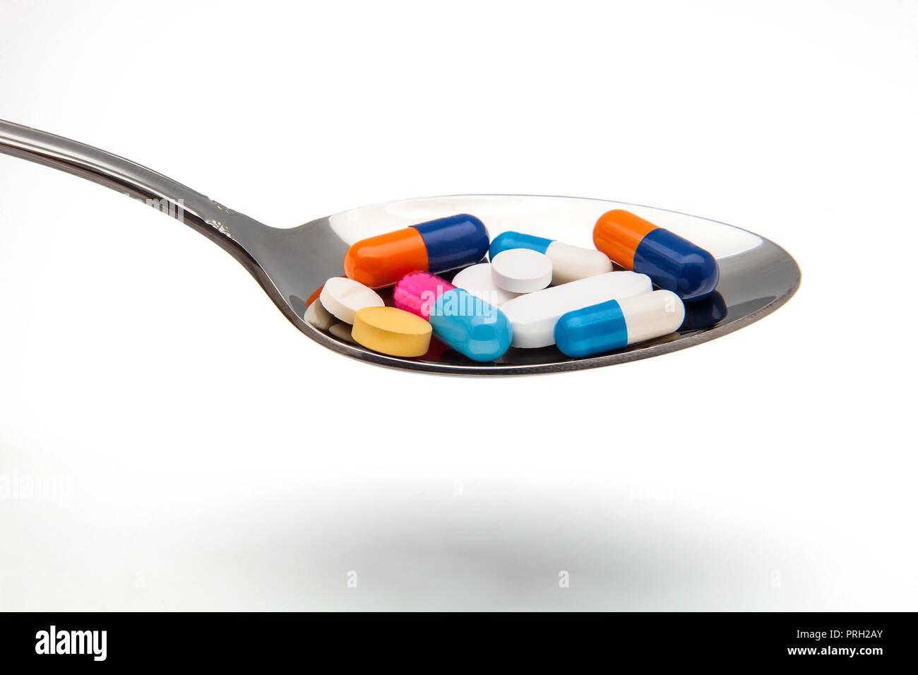 spoon with dose of tablets and capsules Stock Photo