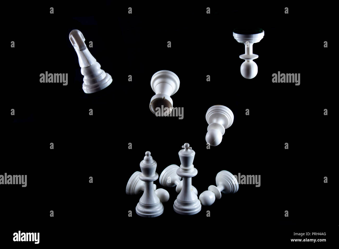 Flying white chess pieces isolated on black background, Queen and King standing front. Stock Photo