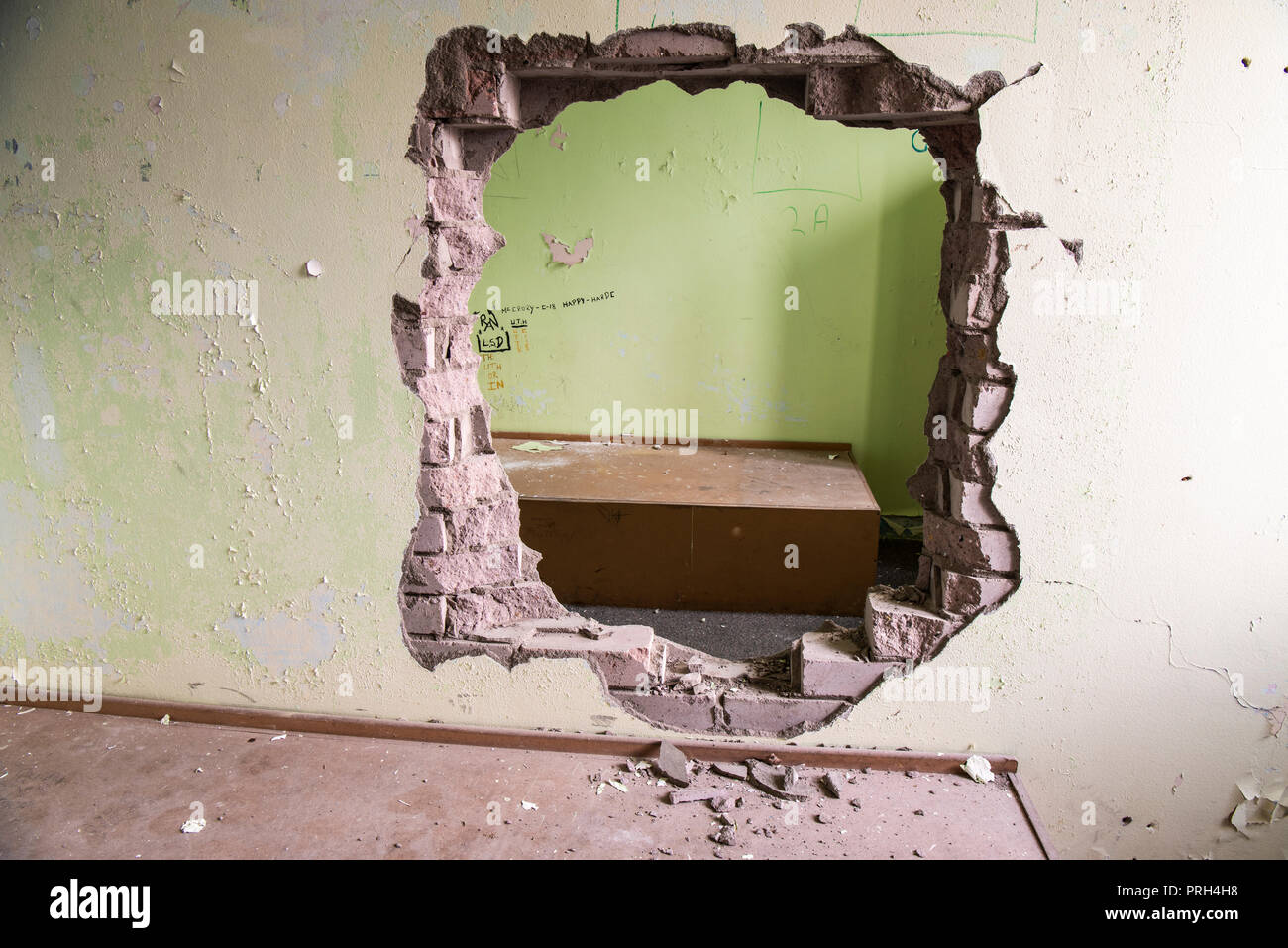 Hole punched through the wall between two prison cells Stock Photo