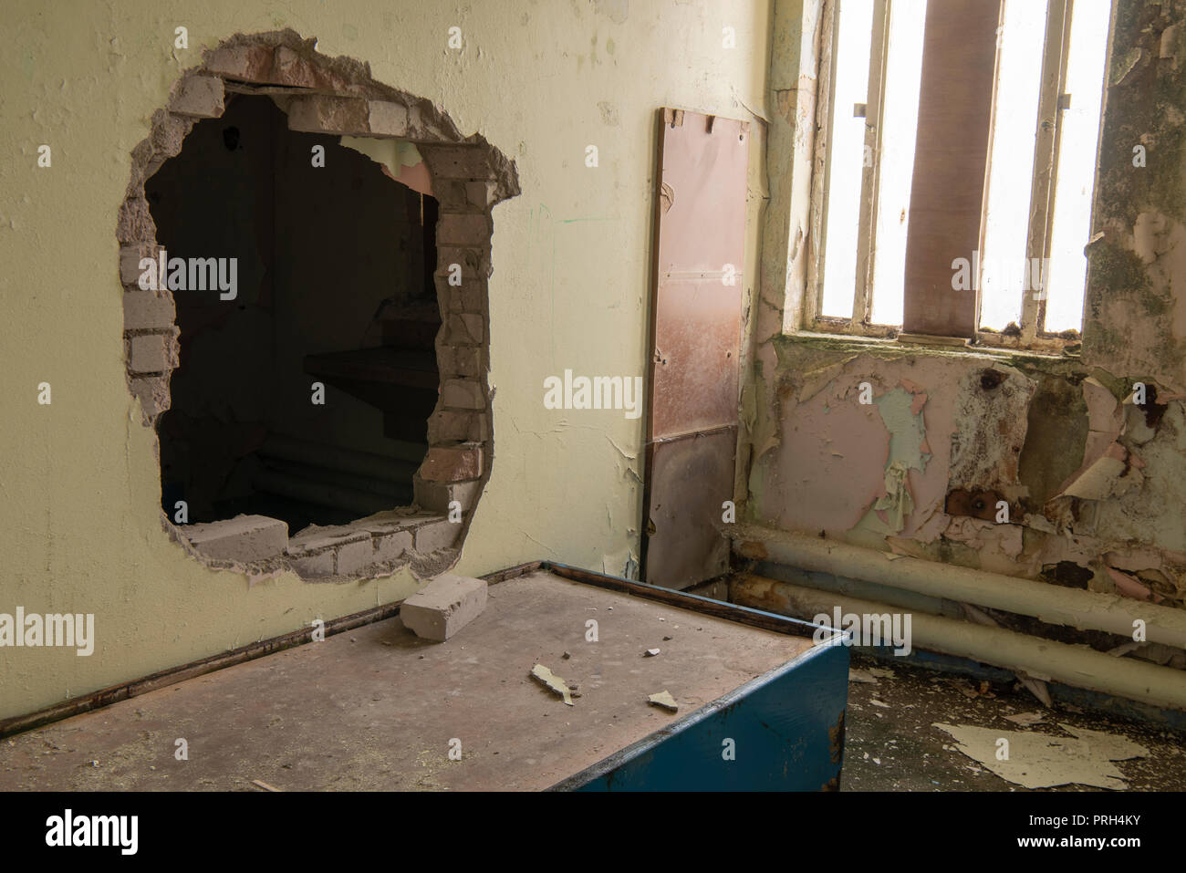 Hole punched through the wall of a prison cell for an escape. Stock Photo