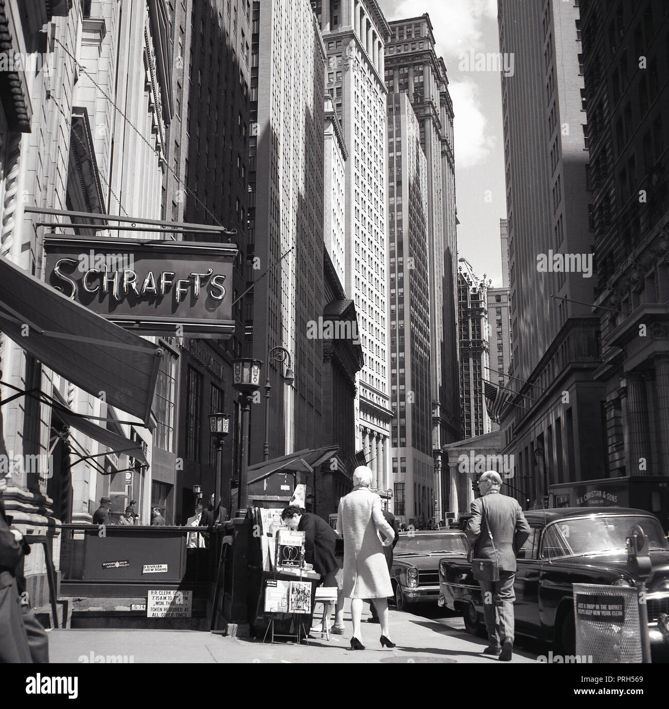 1950s, historical, New York city, Manhattan and a view down Wall street  showing the tall office blocks and skyscrapers of the financial district  and a sign for Schrafft's, a famous chain of