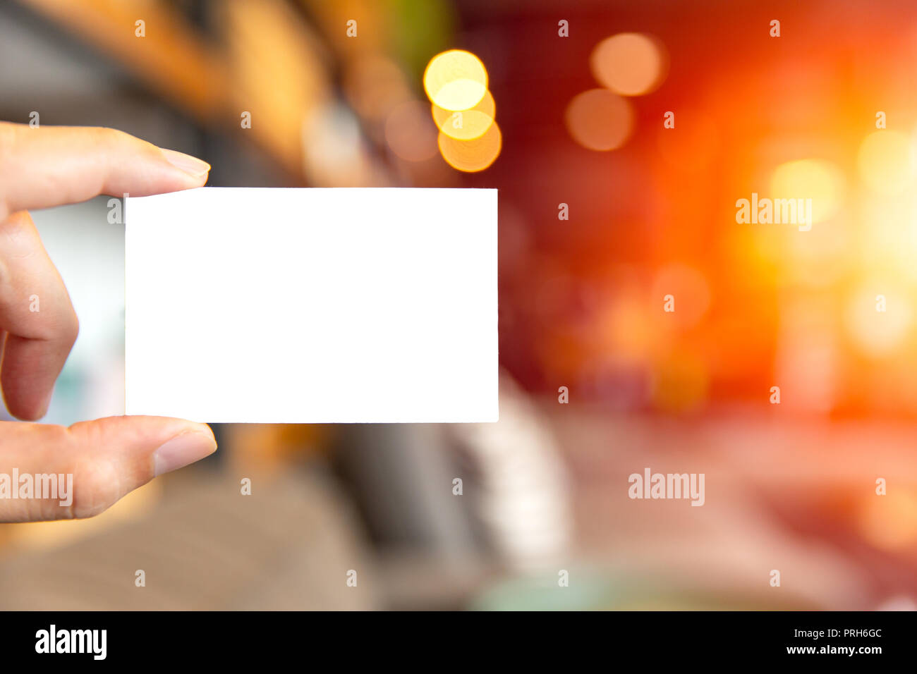 hand holding blank white business card with blur cafe background Stock Photo