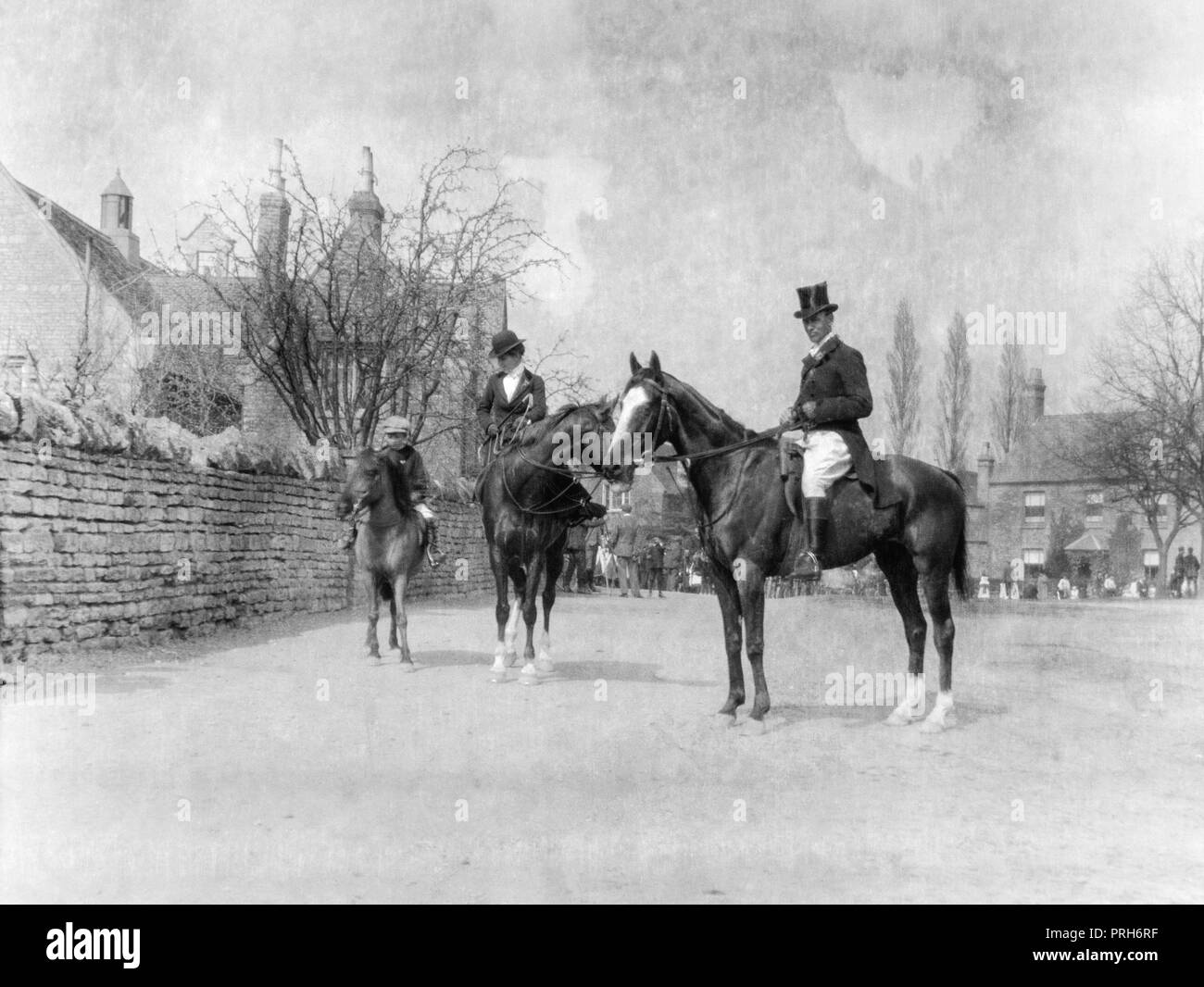 An early photograph showing a man and woman on horseback at the beginning of a foxhunt in an English town. Stock Photo