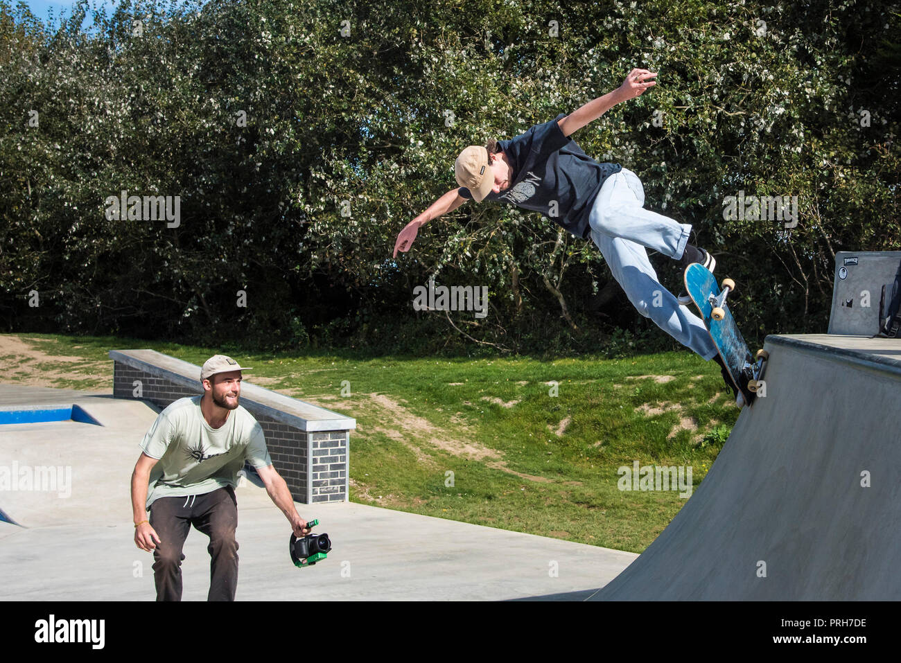 A skateboarder being filmed performing a trick on a ramp at Concrete Waves in Newquay in Cornwall. Stock Photo