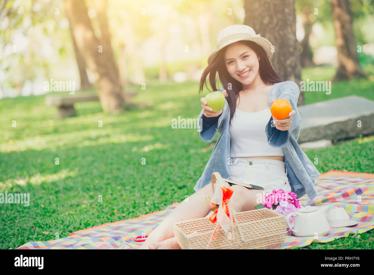 cute teen giving fruit for eating healthy food when picnic outdoor park concept. Stock Photo
