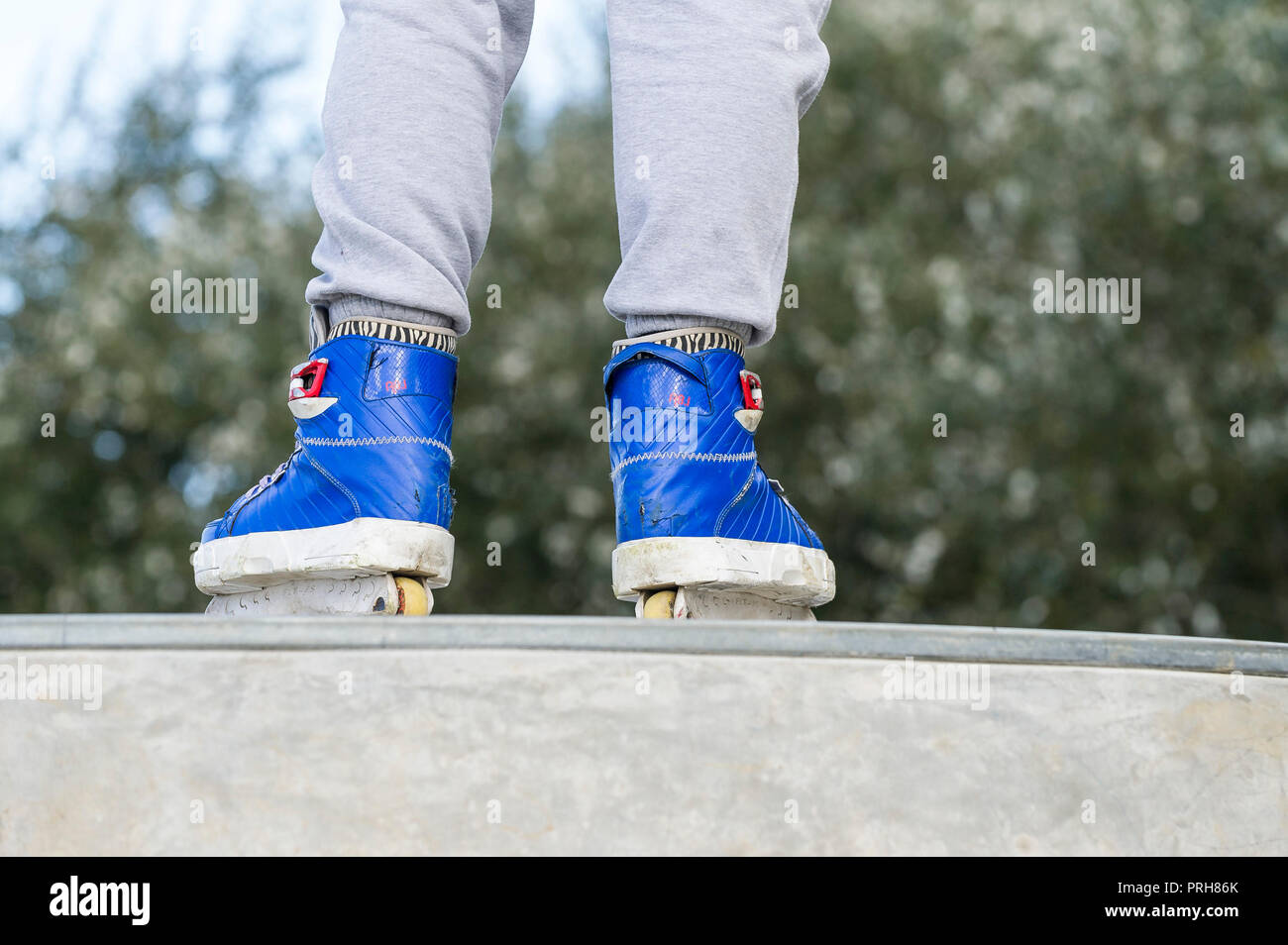 A closeup of Inline skates worn by a skater standing on a deck at