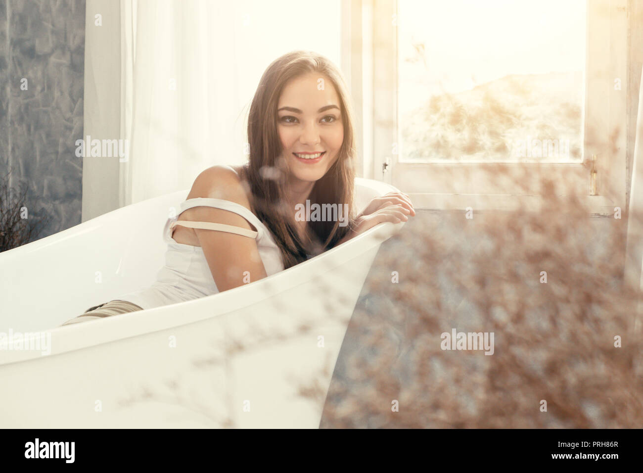 cute teen woman smiling waiting in the bathtub bathroom Stock Photo