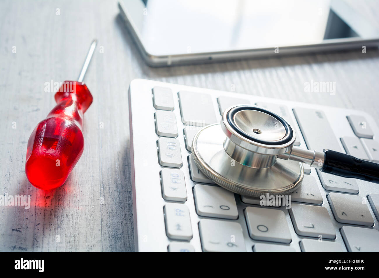 Stethoscope On A Keyboard Next To A Screwdriver And A Smartphone