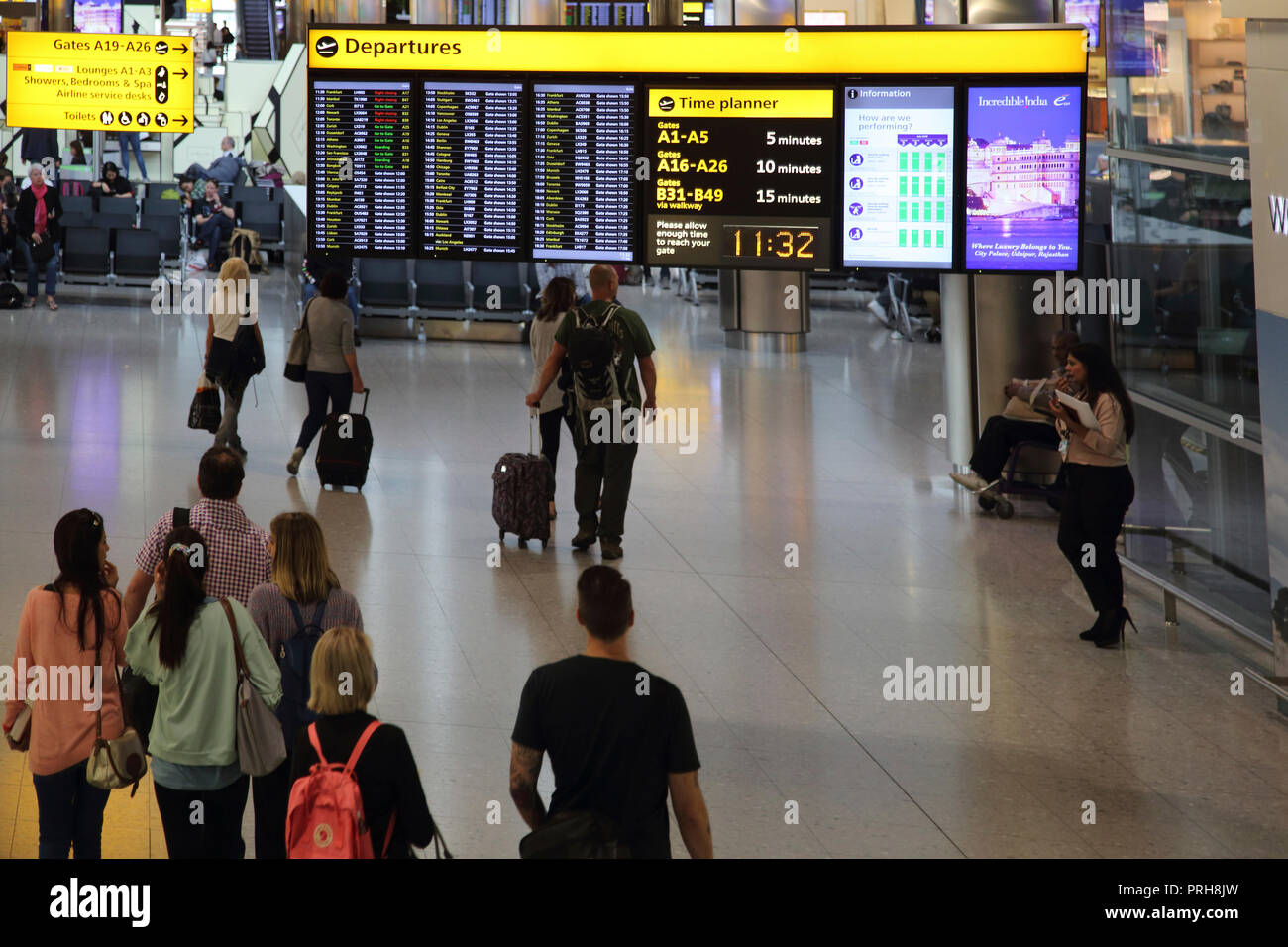 England Heathrow Airport Terminal Two Passengers Heading Toward Departure Lounge Departures Board Stock Photo