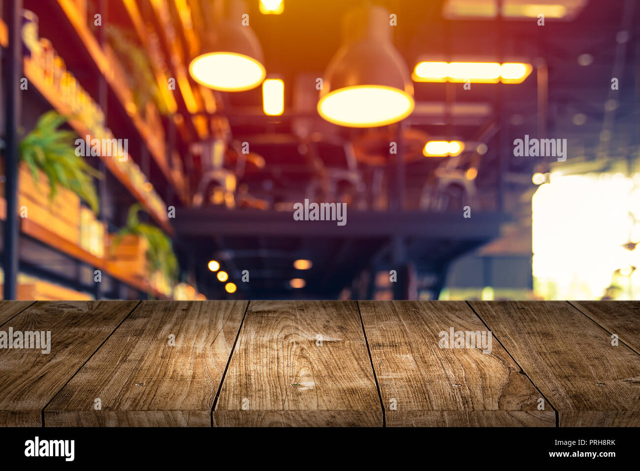 wooden table foreground with blurred cafe restaurant lights background for montage products. Stock Photo