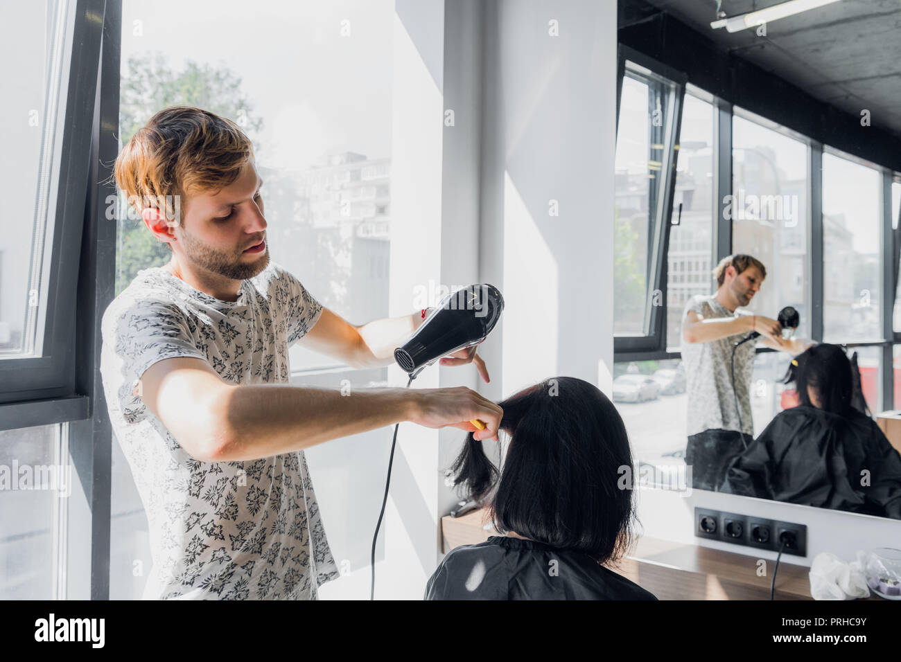 Portrait of happy hairdresser holding comb and blow dryer in salon Stock Photo Alamy