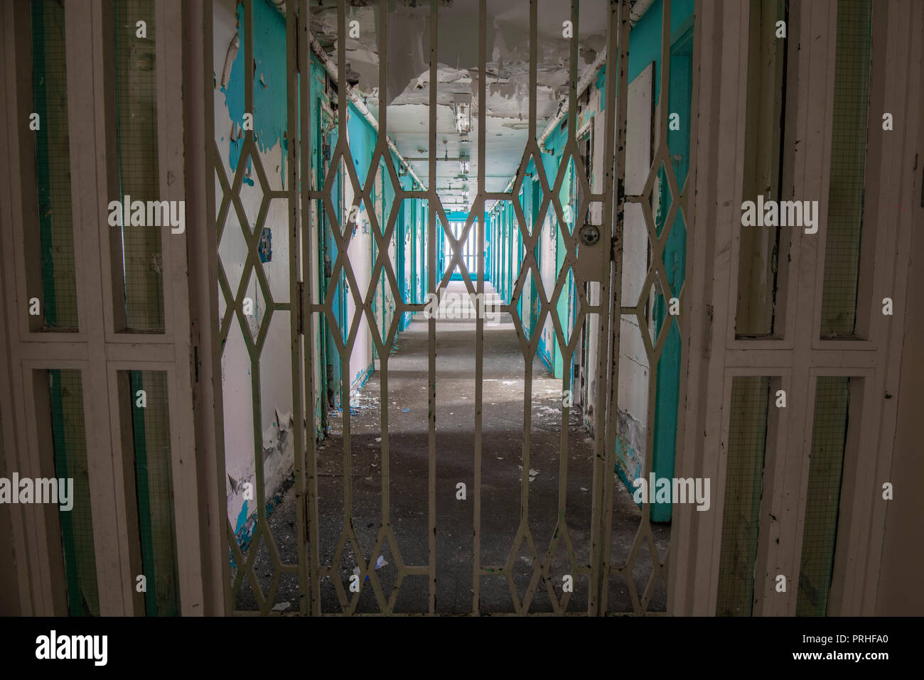 Steel gate across the corridor of prison cell doors inside an abandoned prison. Stock Photo