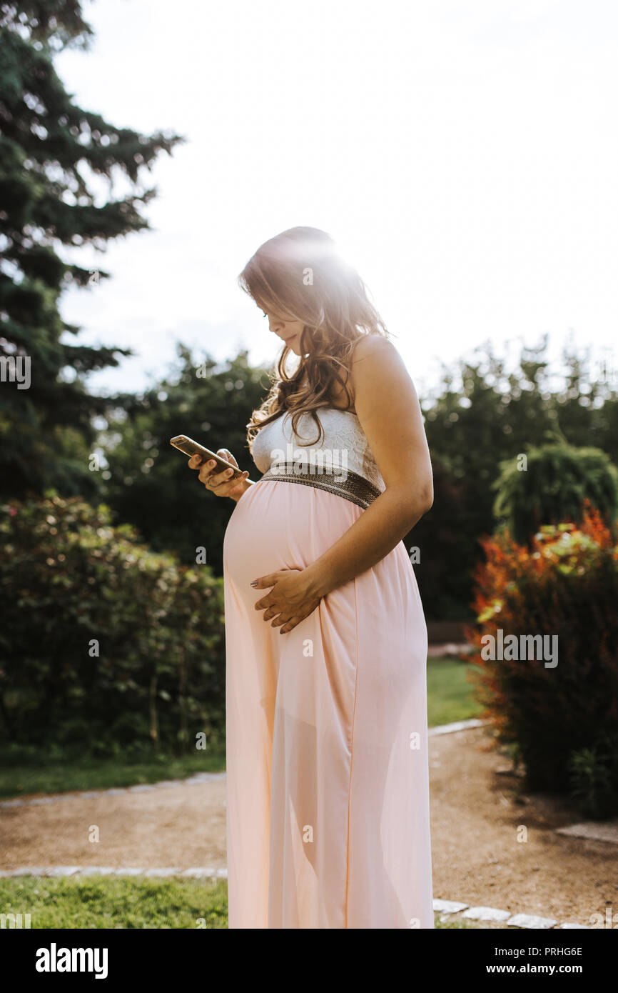 portrait of beautiful pregnant woman is holding her belly and looking ...