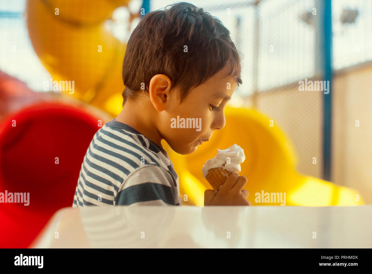 Boy eating a scoop of ice cream in the playground Stock Photo