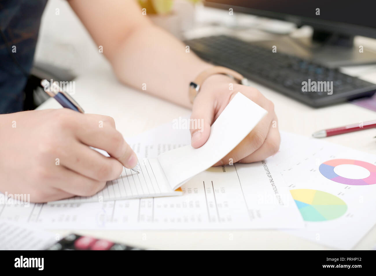 Man is writing work on notepad with pen in hand. Stock Photo