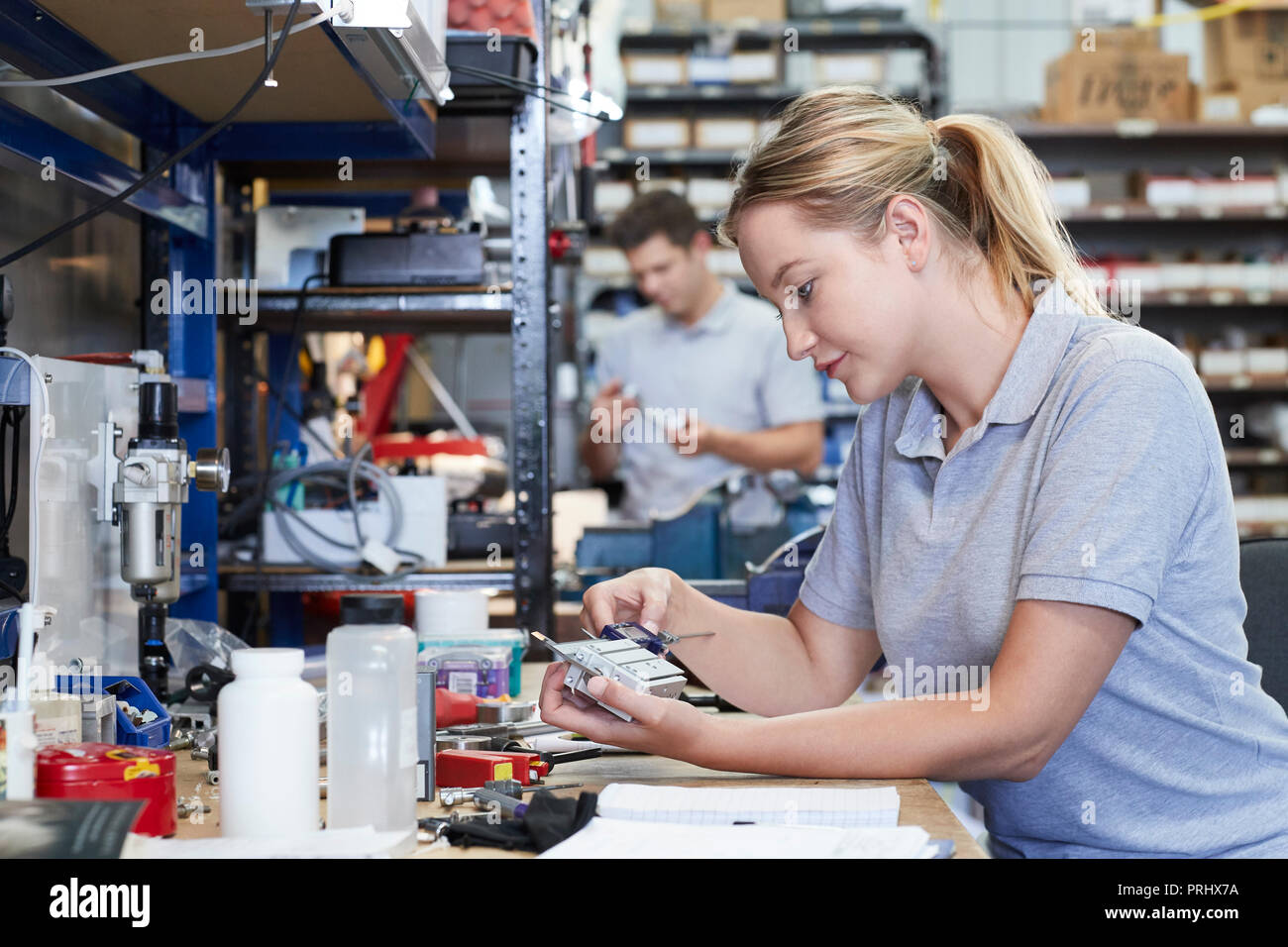 Female Engineer In Factory Measuring Component At Work Bench Using Micrometer Stock Photo