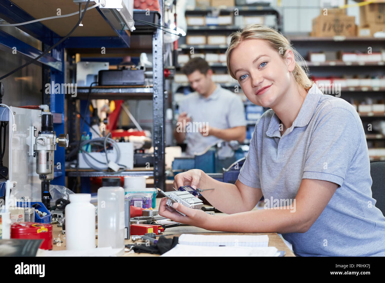 Portrait Of Female Engineer In Factory Measuring Component At Work Bench Using Micrometer Stock Photo
