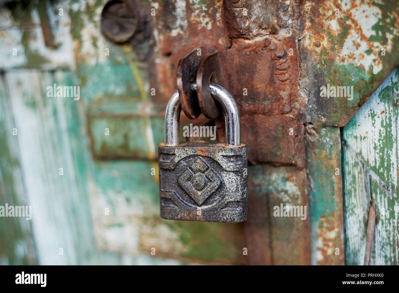 Old metallic padlock on wood,I have not painted the gate. Green shabby paint. Stock Photo