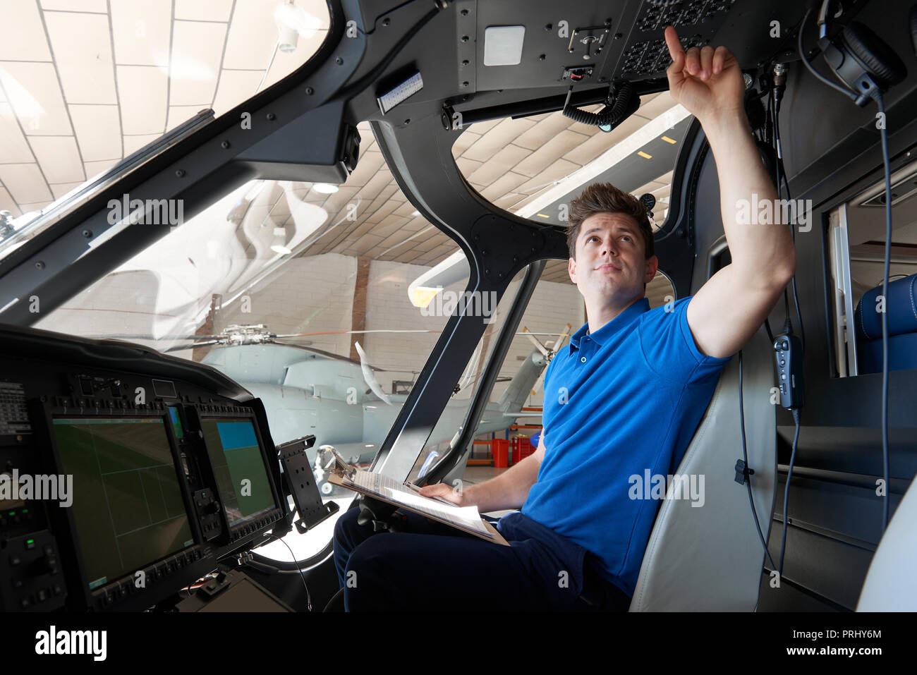 Male Aero Engineer With Clipboard Working In Helicopter Cockpit Stock Photo