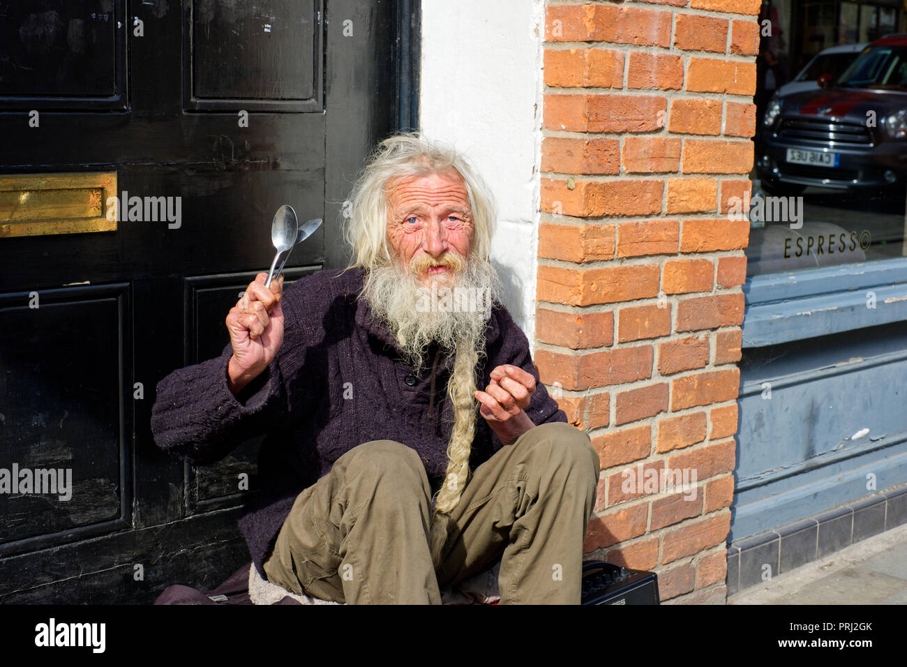 A Street Musician playing his spoons with background music on the high street in Wells, Somerset, UK Stock Photo