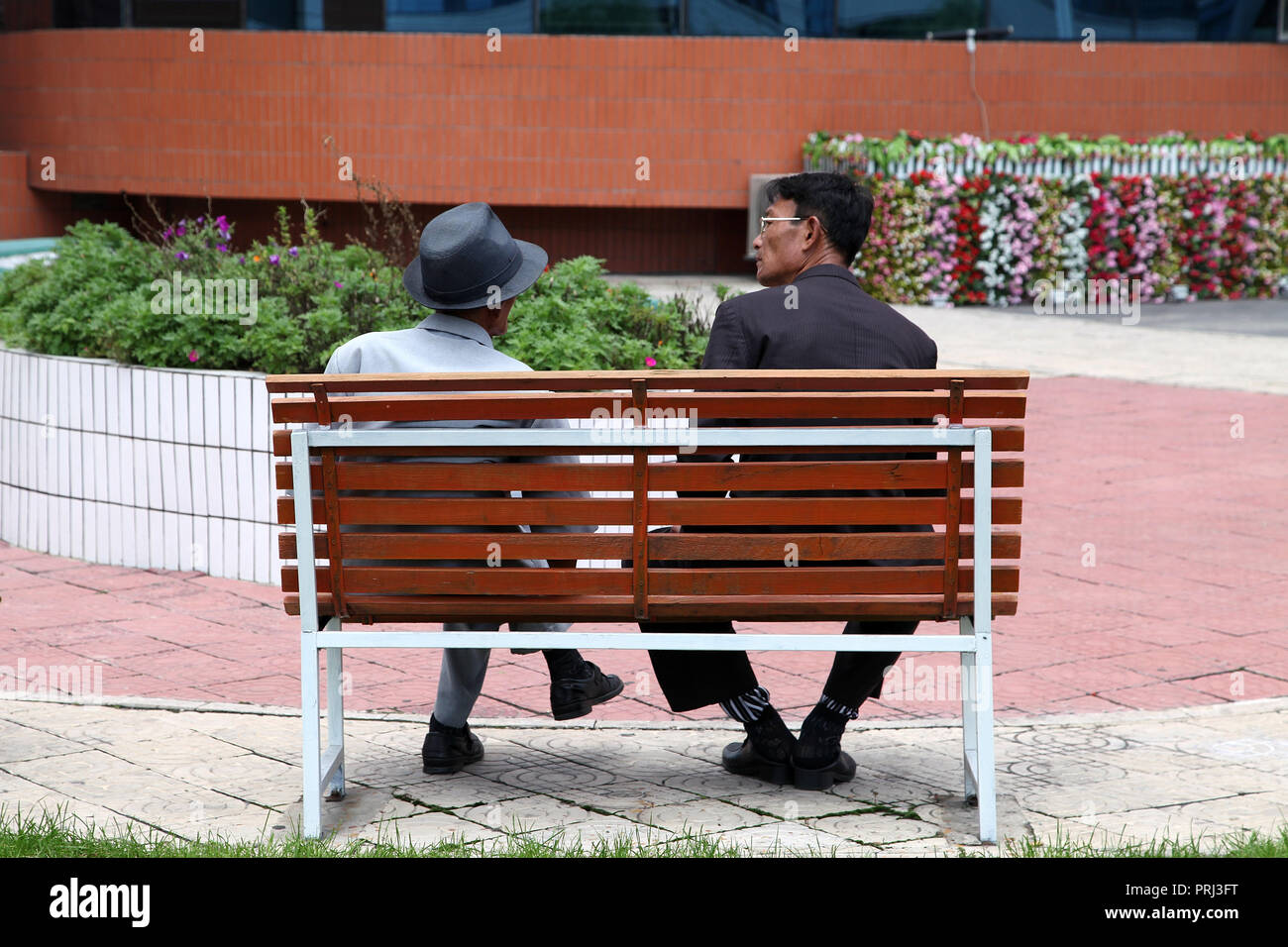 Two gentlemen chatting on a seat at Mirae Scientists Street in Pyongyang Stock Photo