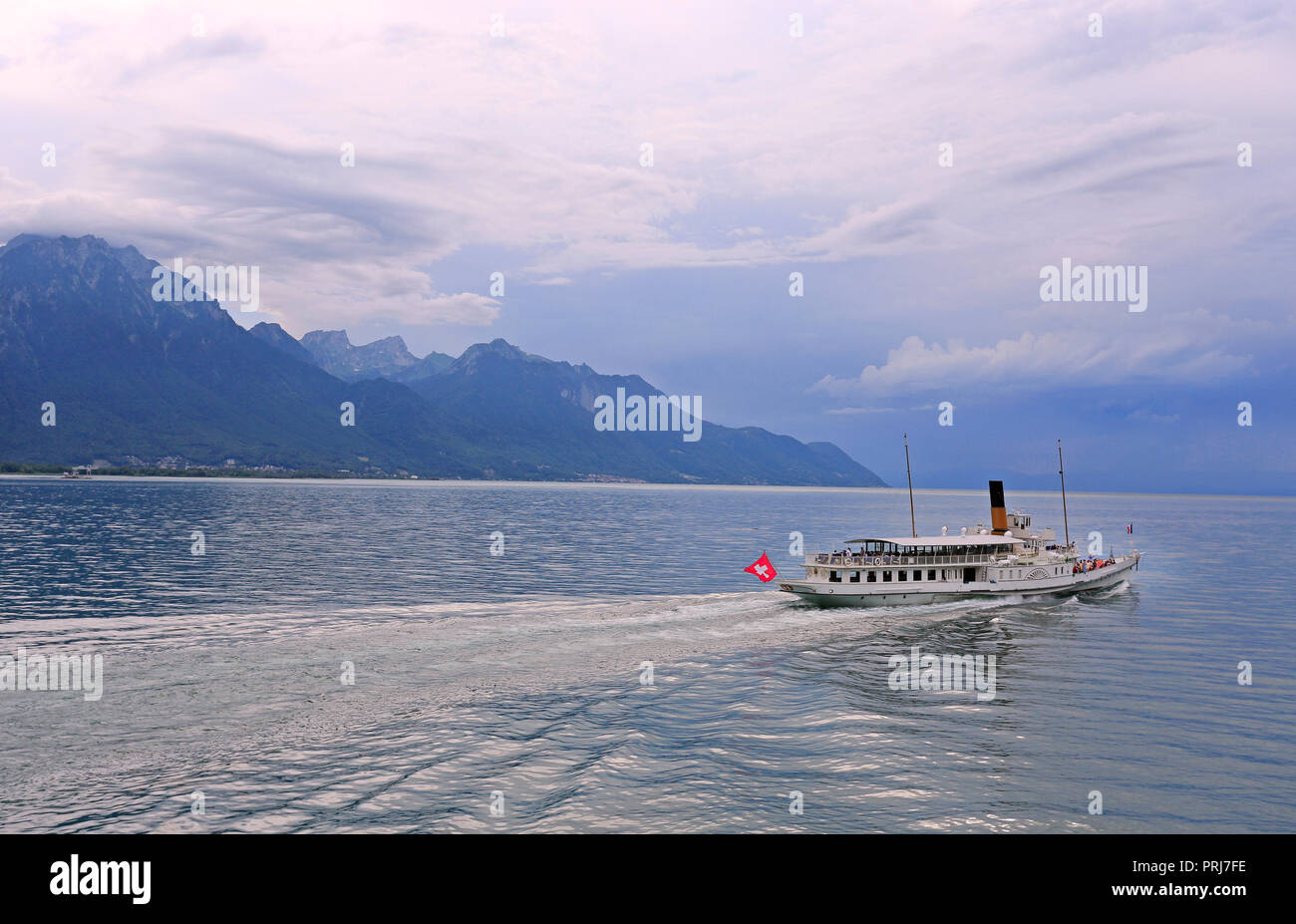 Cruise steamer on Lake Geneva against the background of beautiful mountains and reflection in the water before the storm, Switzerland Stock Photo