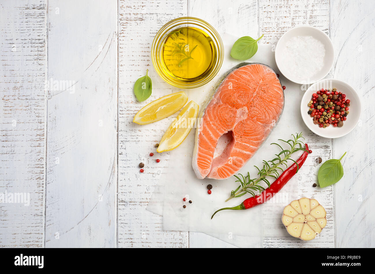 Fresh raw salmon steak with lemon, olive oil and spices on rustic wooden background. Ingredients for making healthy dinner. Healthy diet concept. Stock Photo