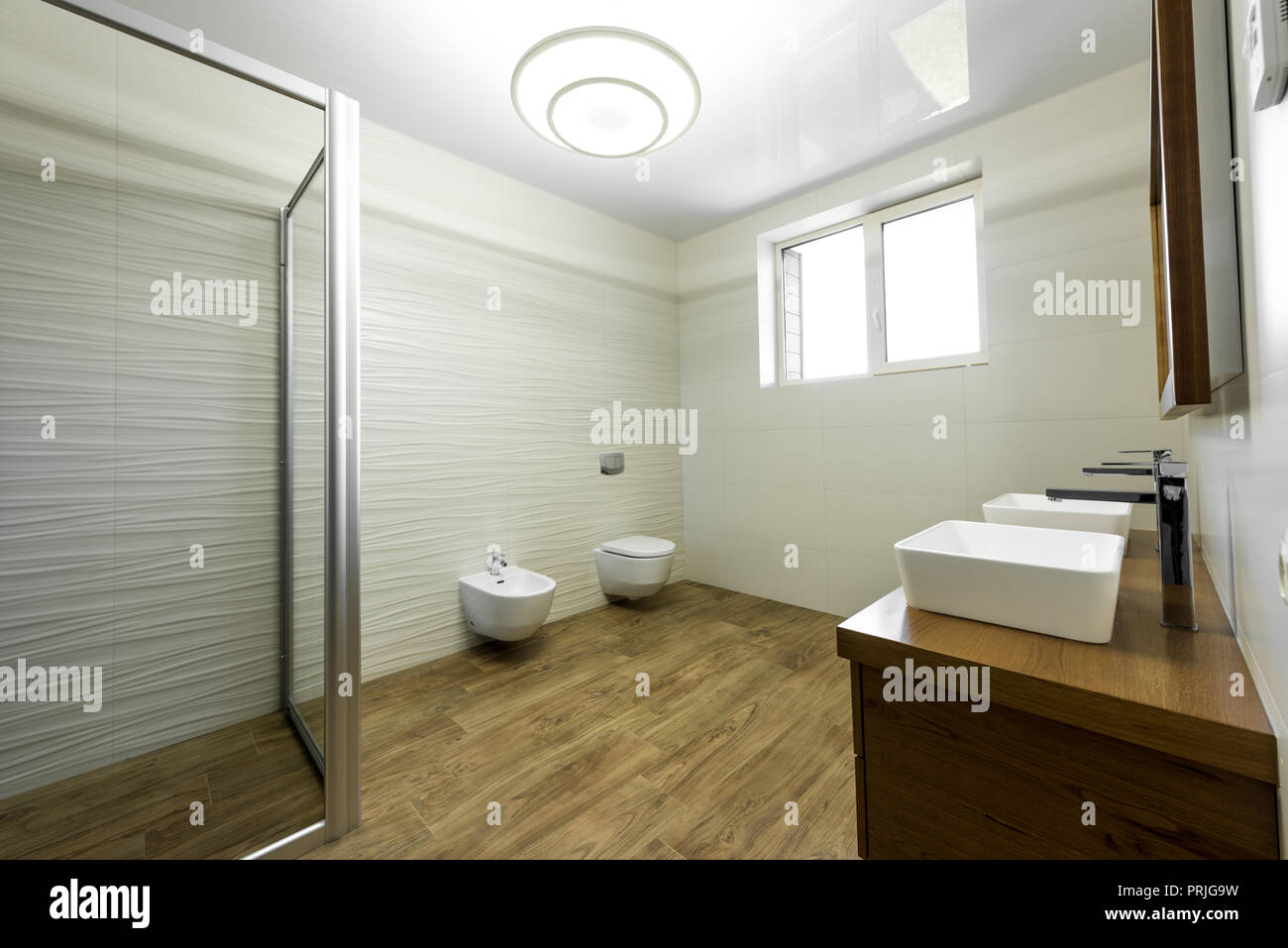 interior of modern bathroom with glass shower, toilet, bidet and two sinks Stock Photo