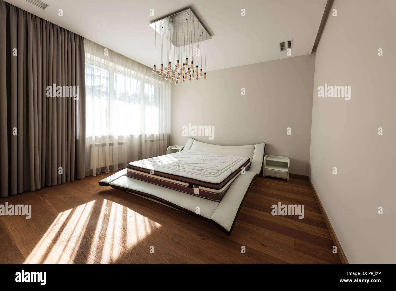 interior of modern bedroom with bed and light bulbs on ceiling Stock Photo