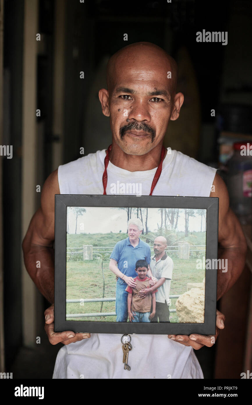 Portrait of man who lost his wife and daughter in the 2004 boxing day tsunami. He holds a photo of US President Bill Clinton with him and his son. Stock Photo