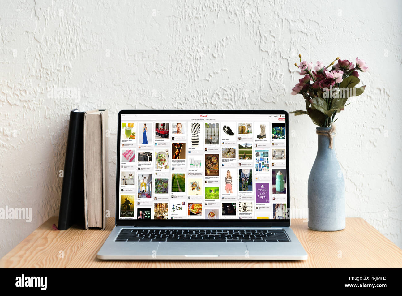 Laptop With Pinterest Website On Screen Books And Flowers In Vase