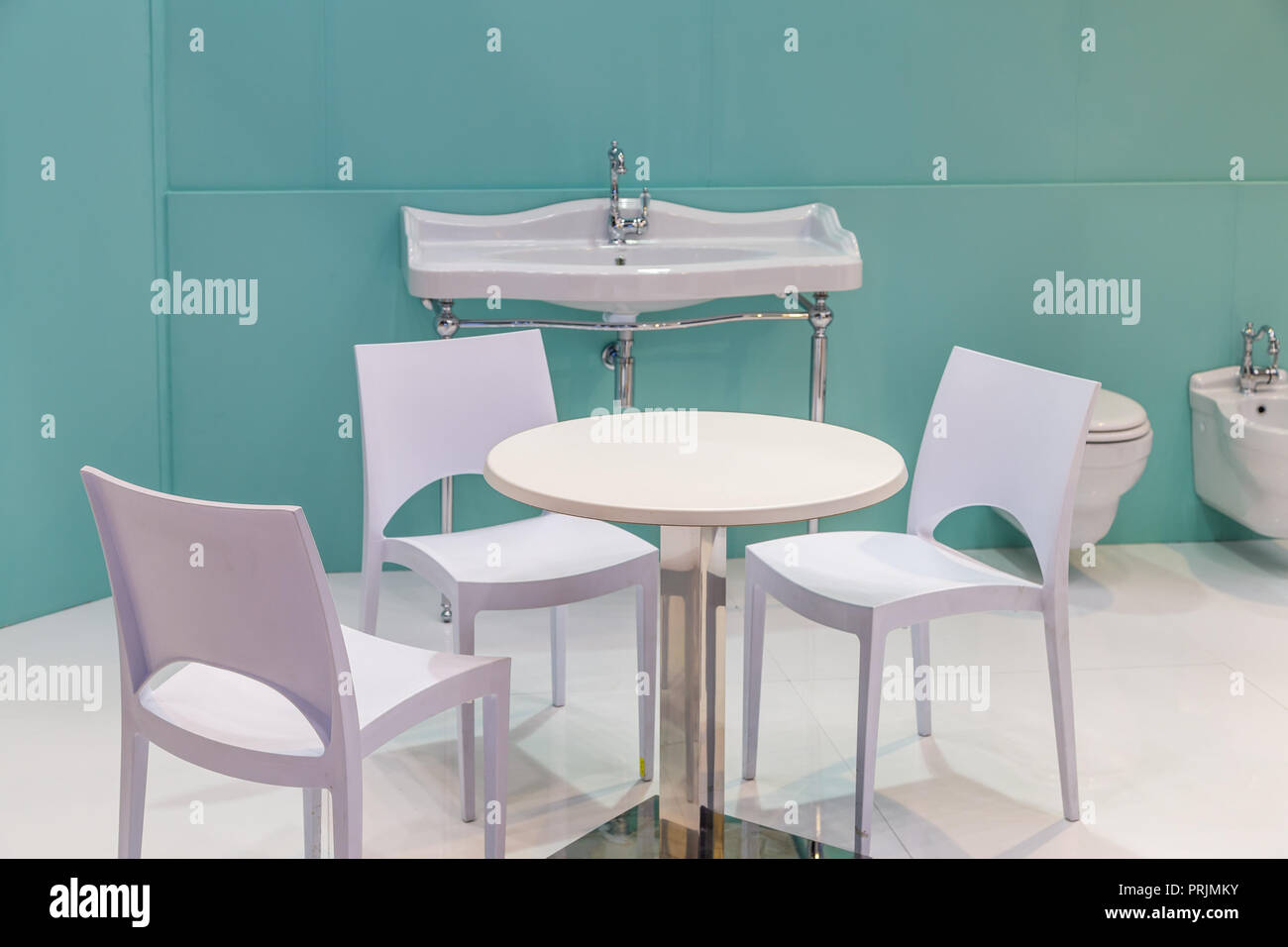 table and chairs in a bathroom with sink, bidet and toilet bowl Stock ...