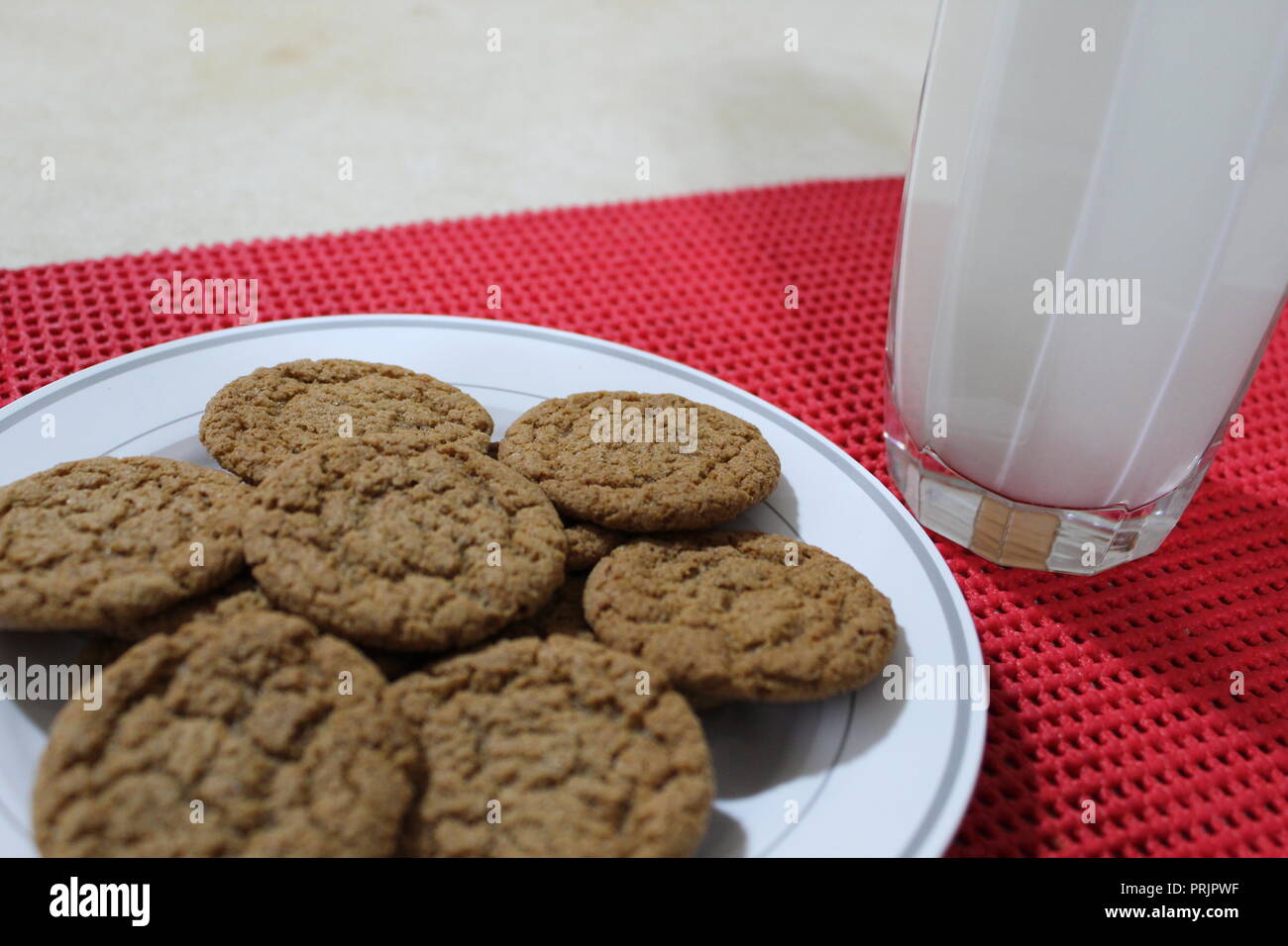 Pumpkin spice cookies and milk on a red placemat Stock Photo