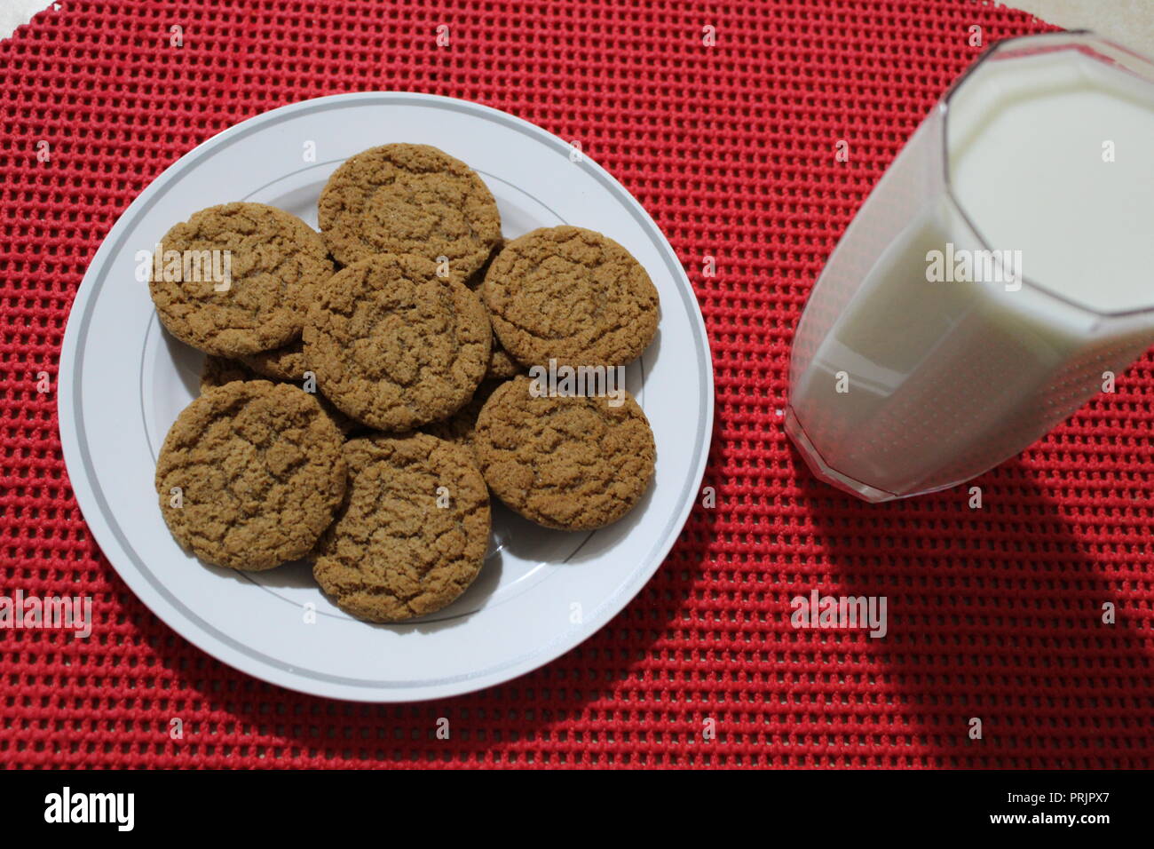 Pumpkin spice cookies and milk on a red placemat Stock Photo