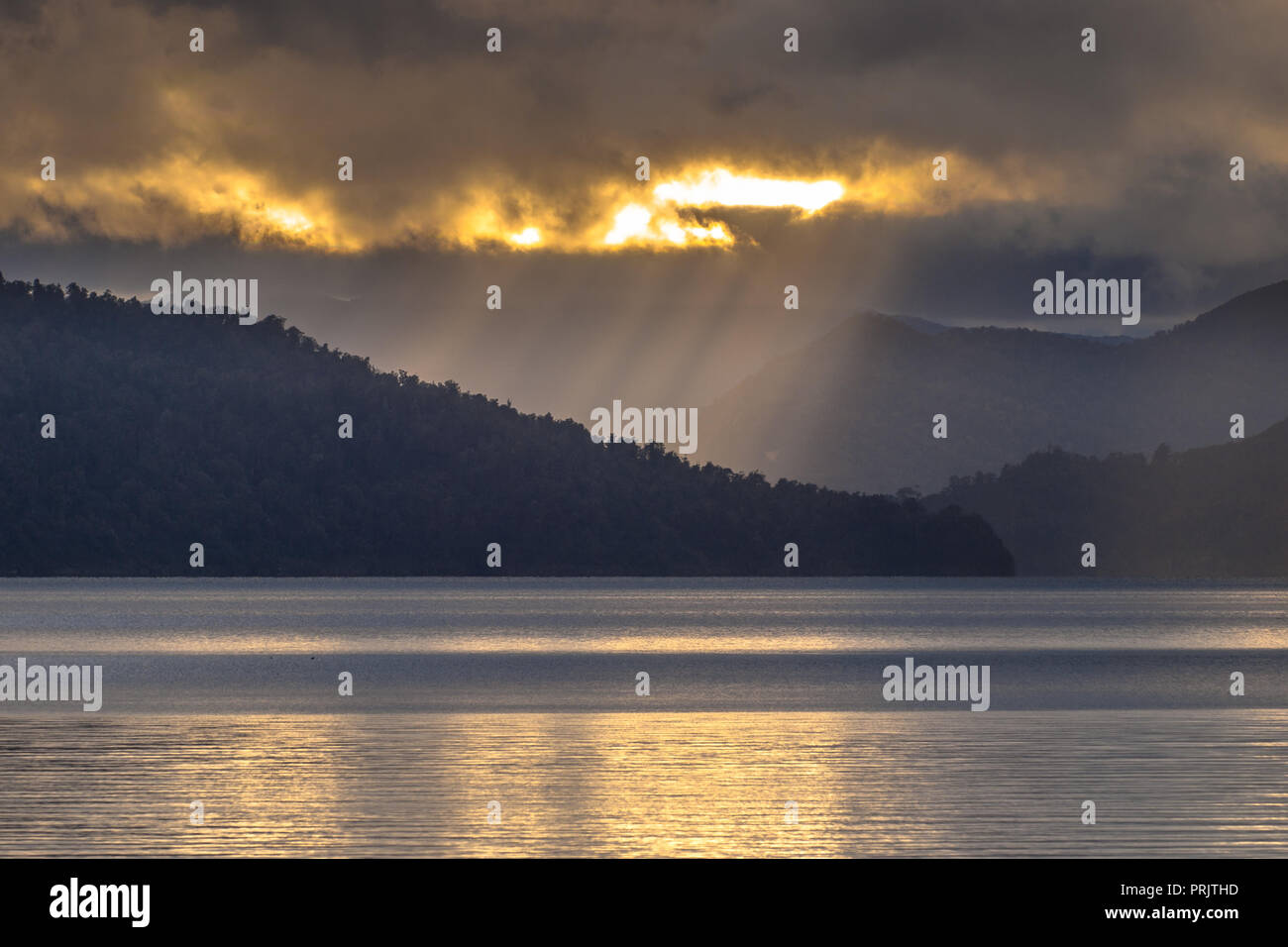 Rays of sun falling through the clouds over pristine mountain lake Wakaremoana in New Zealand Stock Photo