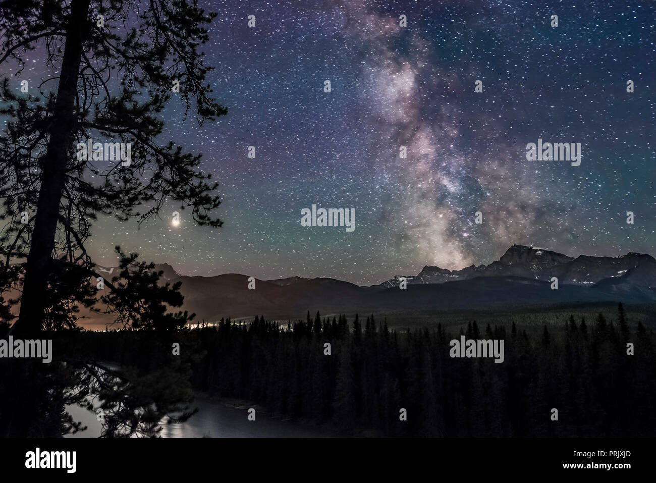 The Milky Way and Galactic Centre (right) and Mars (at left, near its brightest for 2018), over the Bow River and Bow Valley, looking south and west t Stock Photo