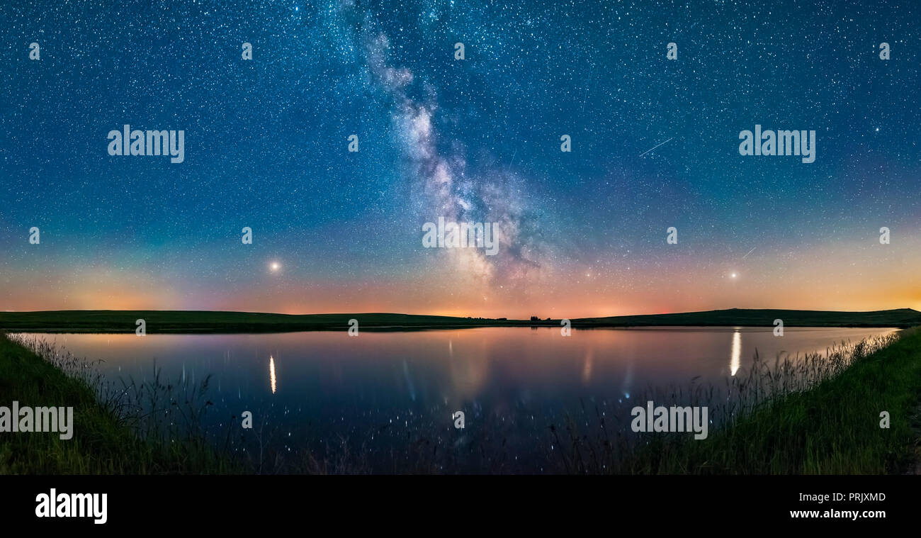 A 160° panorama taken July 5/6 of the summer Milky Way and the array of summer 2018 planets over the prairie pond near home in southern Alberta.   Mar Stock Photo