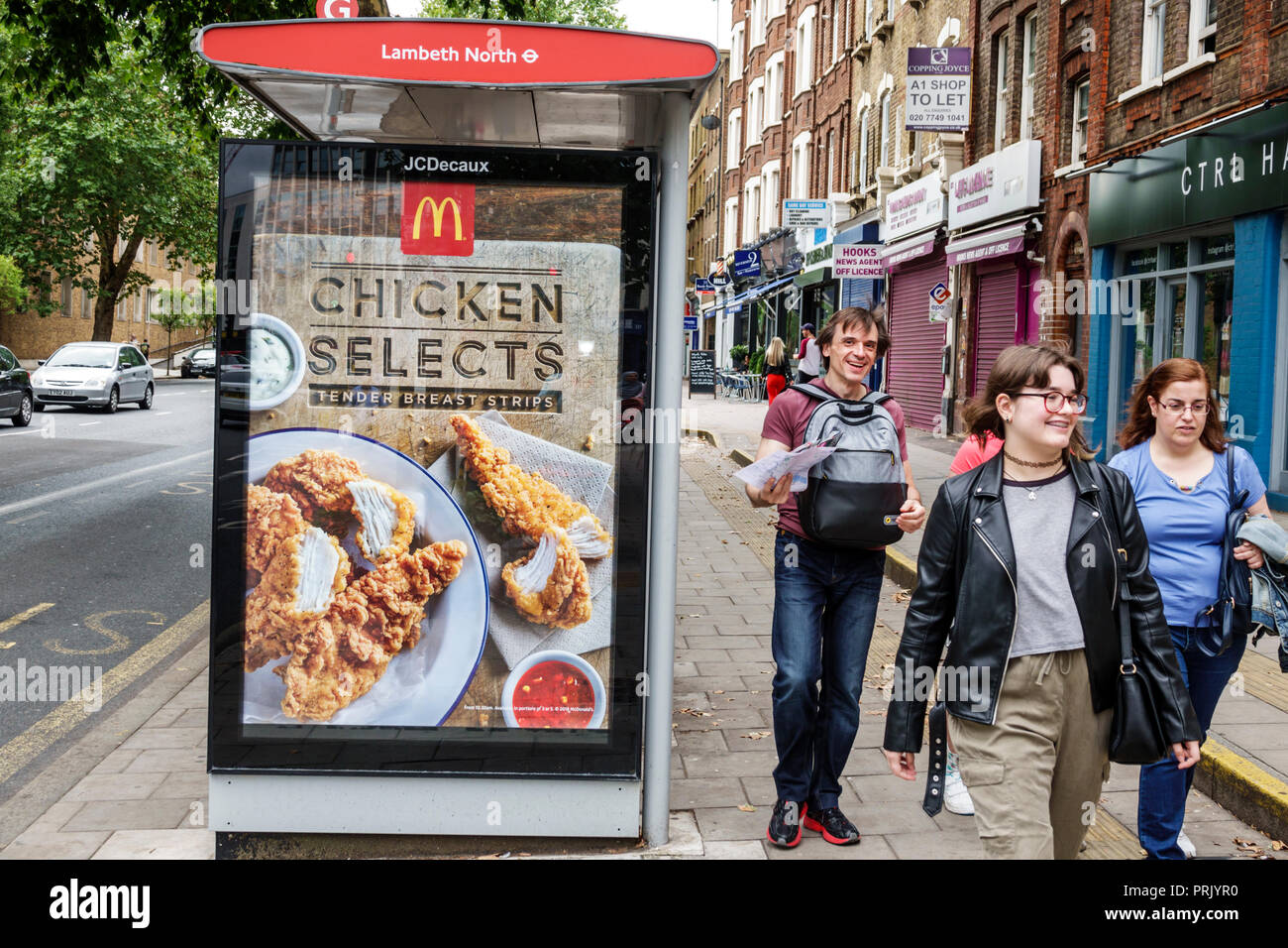 London England,UK,Lambeth North Kennington Road bus stop shelter,McDonald's ad advertising advertisement poster billboard,girls teens teenagers pedest Stock Photo