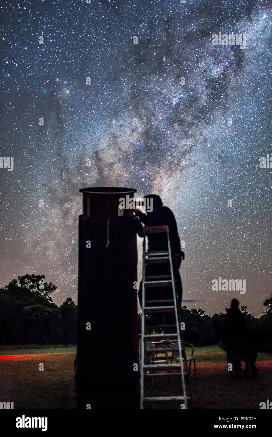 An observer at the 2017 OzSky Star Party peers into the southern sky with the Milky Way galactic centre rising behind him and as a bright backdrop. At Stock Photo