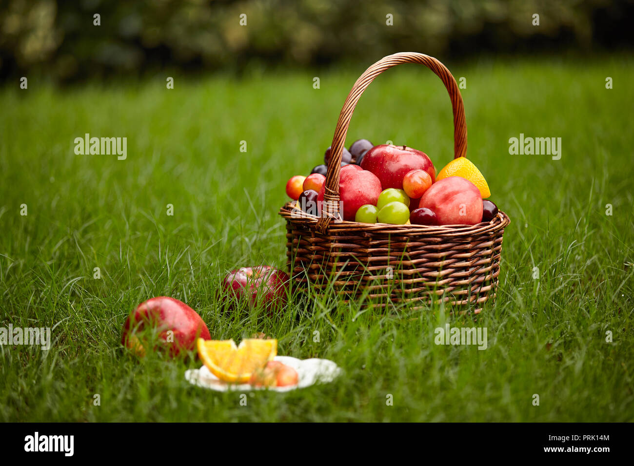 assorted fruits in a basket for picnic on grass. Stock Photo