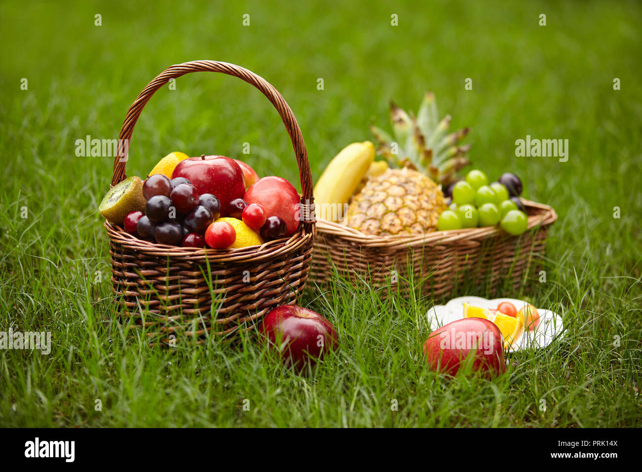 assorted fruits in baskets for picnic on grass. Stock Photo